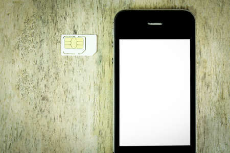 smart phone and sim card on wood background, top view