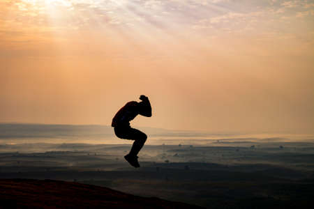 young man is jumping on top of the mountainの写真素材