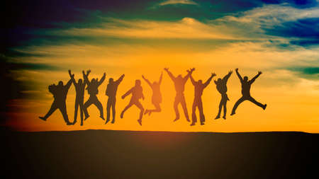 group of young people is jumping on top of the mountainの写真素材