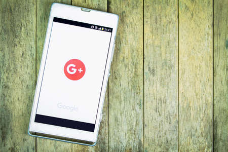 BUNG KAN, THAILAND - FEBRUARY 19, 2016: smart phone display google plus app on wood background, space for captionのeditorial素材