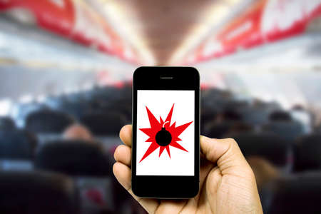 people holding smart phone on blurred cabin crew airplane background with bomb icon on screen
