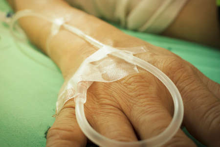 old man hand is receiving patient intravenous saline, vintage tone