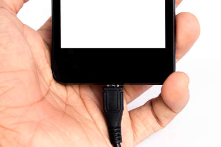 human's hand holding smart phone is charging on white backgroundの写真素材