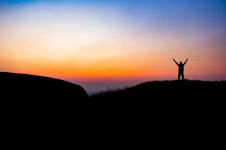 The man is show his hand in the sky at the morning on the mountainの写真素材
