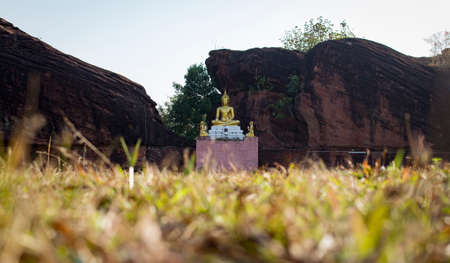 Gold buddha with big rock on background, blurred foregroundの写真素材