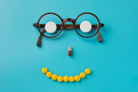 pills. glasses, blue background. Black Eye Glasses with white pills on blue background.の写真素材