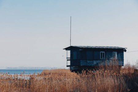 green house on the shore of a large lake. Boat station amidst grass and waterの写真素材