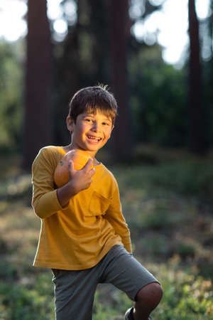 Portrait of a boy in nature with a pumpkin in his hands. yellow on the background of yellowの写真素材