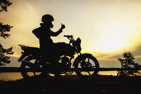 silhouette of a girl on a motorcycle at sunsetの写真素材