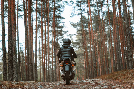 a woman on a motorcycle in nature. motorcyclist walk through the forestの写真素材