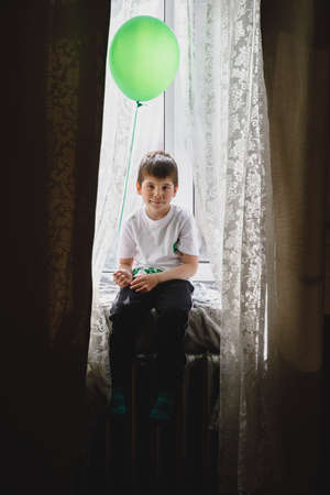 boy with balloon at home by the window.の写真素材