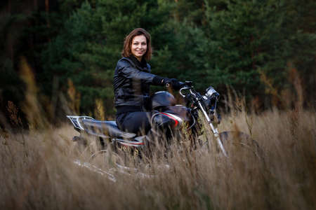 woman on a motorbike in nature. biker motorcycle ride through the woodsの写真素材