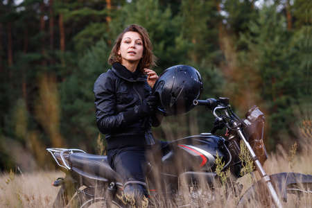 woman on a motorbike in nature. biker motorcycle ride through the woodsの写真素材