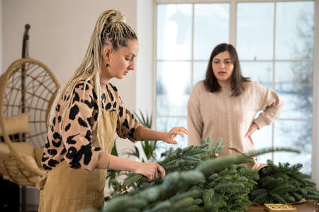 DIY Christmas composition from nobilis. Wreath decor for holiday decorations. Girls at a workshop on making floristry from tree branchesの写真素材