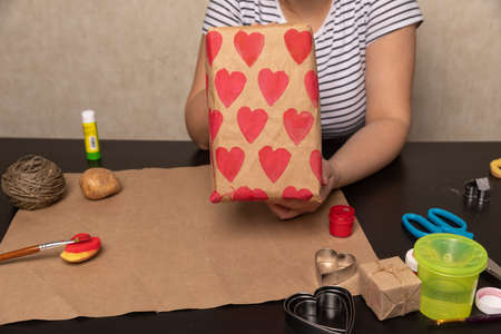 heart shaped potato stamp on craft paper. The process of decorating a gift for Valentines Day....