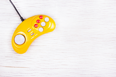 Video game console GamePad on a white wooden table. Yellow  retro GamePad. Copy space.