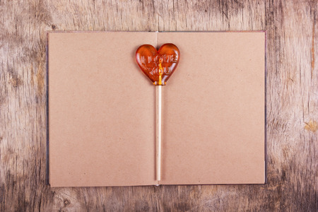 Lollipop in the shape of a heart and an old diary with blank pages. St. Valentine's Day.の写真素材