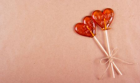Two lollipop in the shape of a heart on a background of brown recycled paper. St. Valentine's Day. Copy spaceの写真素材