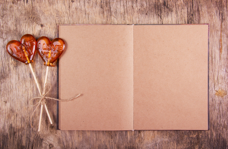 Open notebook with blank pages and two lollipop in the shape of a heart. St. Valentine's Day. The book of recycled paper with a clean slate. Copy spaceの写真素材