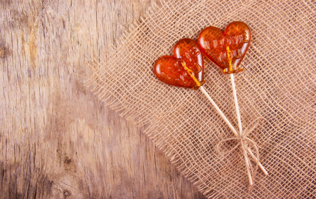 Two lollipop in heart shape on old wooden background. Copy spaceの写真素材