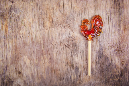 Cock on a stick on the old wooden background. Russian candies. Lollipop in the shape of a rooster. Copy space.の写真素材