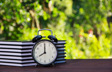 A stack of books and an alarm clock on the table. Educational concept. School time. Copy spaceの写真素材