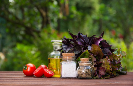 Olive oil, salt and spices. Ingredients for summer salad. Fresh greens and tomatoes for salad.の写真素材