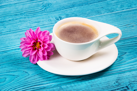 A white cup of coffee on a blue table. Coffee cup and flower.の写真素材