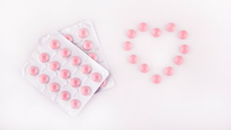 Pink tablets. Heart of pills. Pink tablets in a blister on a white background. Copy spaceの写真素材