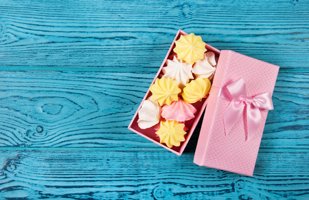 Gift box with meringues on a blue table. Copy spaceの写真素材