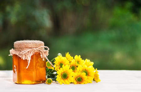 A jar of flower honey and yellow flowers. Fresh homemade honey. Copy space