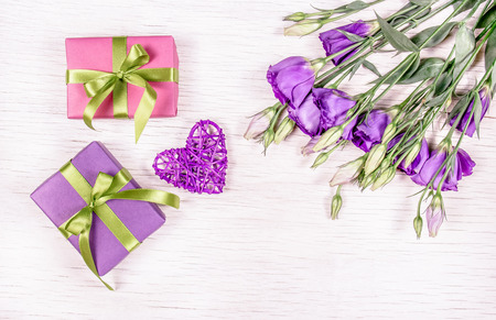 Gifts and flowers. Boxes with gifts and a bouquet of flowers eustoma on a white background. Wicker heart. Romantic concept.の写真素材