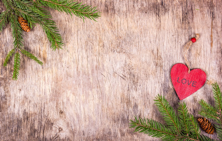 Christmas background with fir branches and a wooden heart on  old wooden board. Copy spaceの写真素材