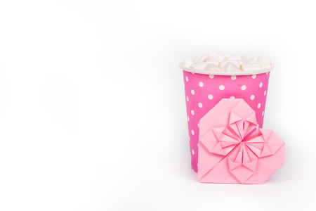 Hot drink with marshmallow in pink paper cup. Pink paper cup and valentine card on white background. Romantic concept. St. Valentine's Day. Copy spaceの写真素材