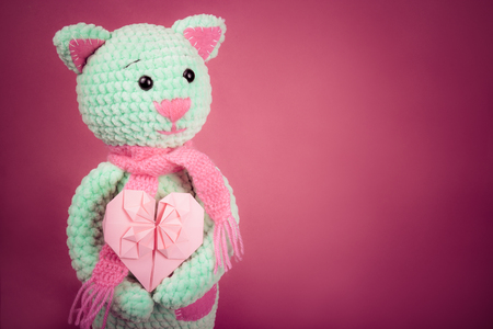 Soft knitted cat and valentine card on pink background. Soft knitted toy. Romantic gift. Copy spaceの写真素材