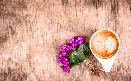 Cup of coffee and bouquet of flowers on wooden background. Delicate violets and fragrant coffee. Mothers Day. Spring concept. Romantic concept.の写真素材