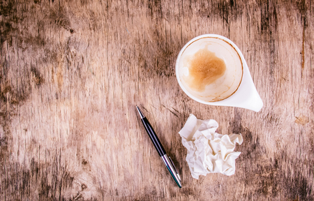 Empty coffee cup, crumpled sheet of paper and pen on wooden table. Crumpled sheet of paper and  pen on wooden background. Dirty coffee cup on wooden table.の写真素材