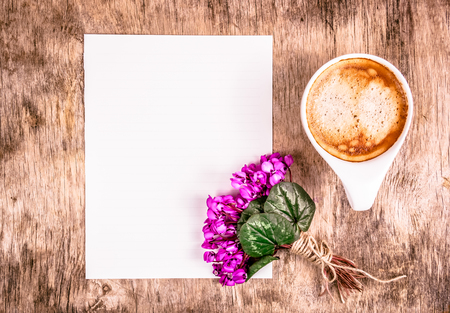 Cup of coffee and flowers. Empty sheet of paper and  cup of coffee on the table.の写真素材