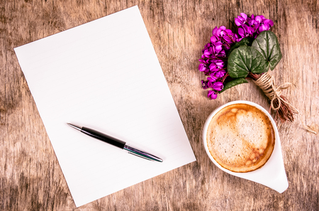Letter, flowers and coffee. Ð¡up of coffee and tender spring flowers. Blank sheet of paper and pen on  wooden background. Copy space. Top viewの写真素材