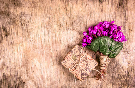 Delicate spring flowers and gift box on wooden background. Primroses. Bouquet of violets and  gift. Romantic concept.の写真素材