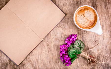 Open book with blank pages, spring flowers and cup of coffee. Coffee and violets on wooden background. Romantic concept.の写真素材