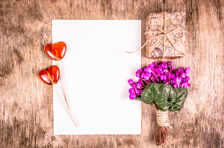 Flowers, candy and gift box on wooden background. Gift for woman. Delicate flowers and gift box. Lollipops in the shape of heart. Romantic concept.の写真素材