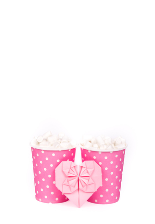 Latte with marshmallows in paper cups and pink heart. Two paper cups on white background. Copy spaceの写真素材
