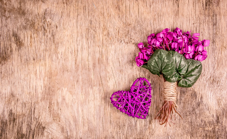 Delicate spring flowers and wicker heart. Romantic concept. Bouquet of violets. Copy spaceの写真素材