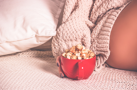 Red cup with caramel popcorn on a knitted plaid. Copy space.  Vintage tintingの写真素材