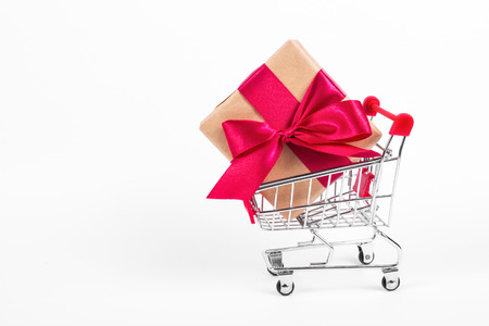 Gift box with  bow in shopping trolley. Shopping cart with large gift box on white backgroundの写真素材