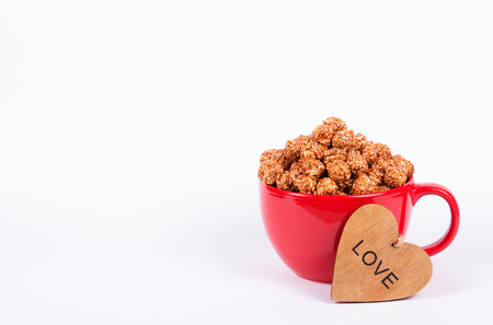 Large red cup of sweet chocolate popcorn. Caramel popcorn in red mug on white background. Popcorn and heart. Copy spaceの写真素材