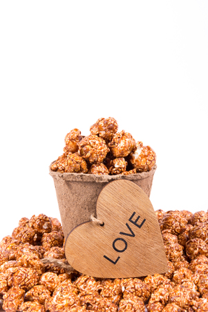 Excellent caramel popcorn in paper cup and wooden heart. Romantic concept.の写真素材