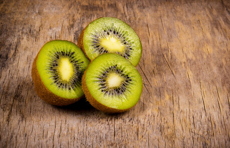 Halves of juicy kiwi on an old wooden board. Vegetarian delicious.の写真素材