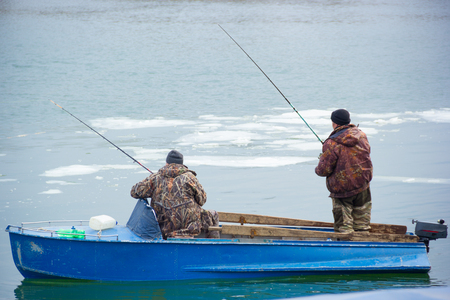Two fishermen in an old motor boat on the river Don. Spring fishing for Donの写真素材